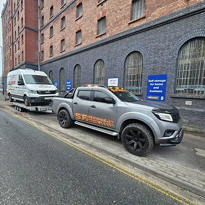 a tow truck towing a truck on a city street