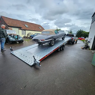 a car on a trailer being towed by a man