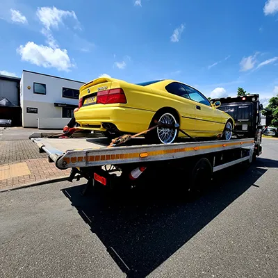 a yellow car is on the back of a tow truck